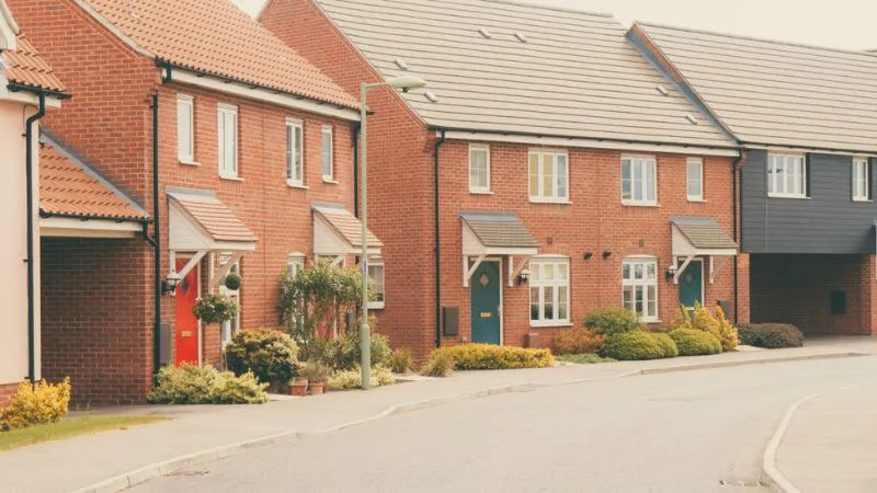 residential street lined with attached brick houses and landscaped front gardens.